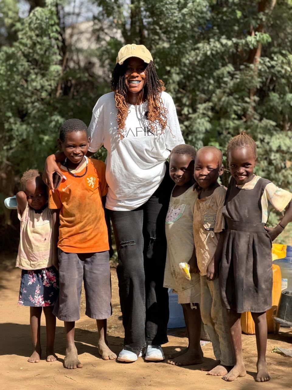 A Rafiki Outreach volunteer smiling with five children in a village